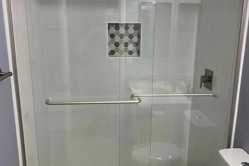 Glass enclosed shower with a mosaic tiled niche and floor