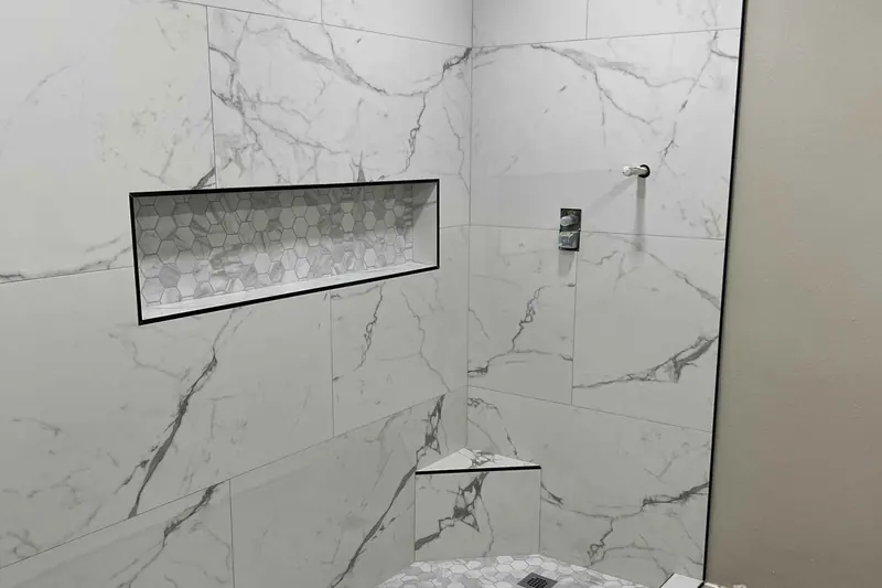 Walk-in shower finished in marble look porcelain with a long recessed niche