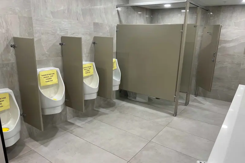 Finished commercial restroom with tiled walls and privacy partitions