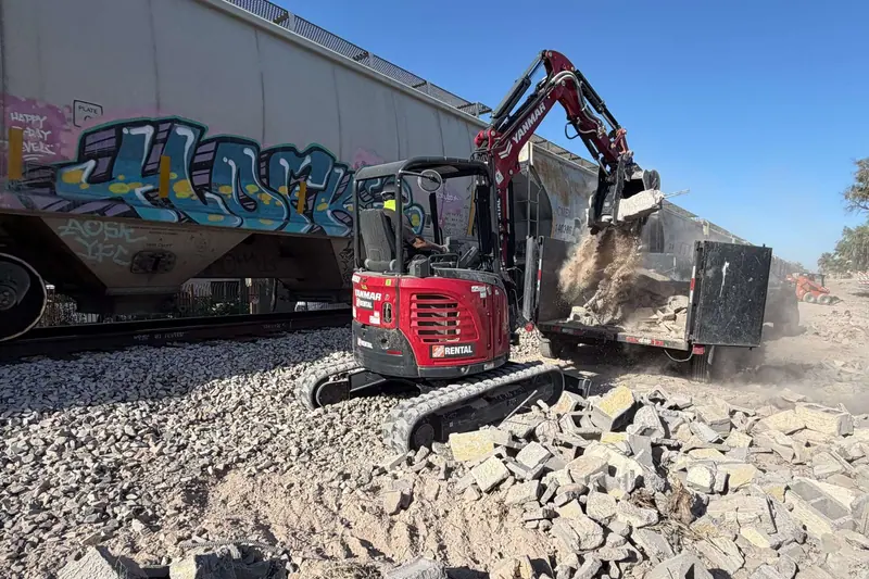 Compact excavator breaking up concrete on a demolition site