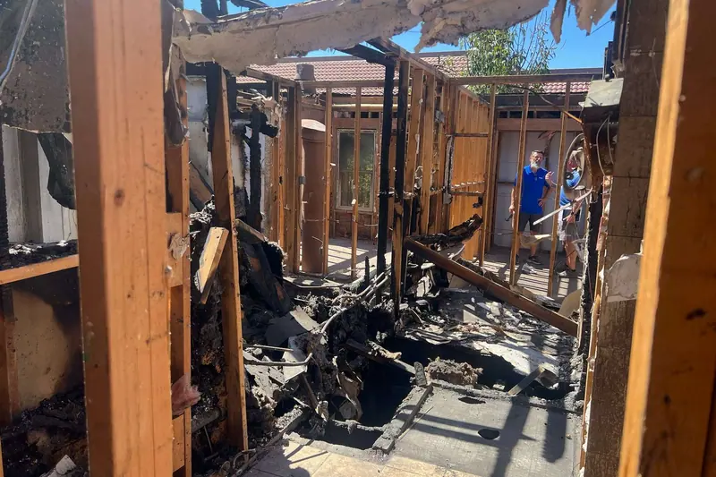 Charred roof framing and burnt debris inside a fire damaged structure