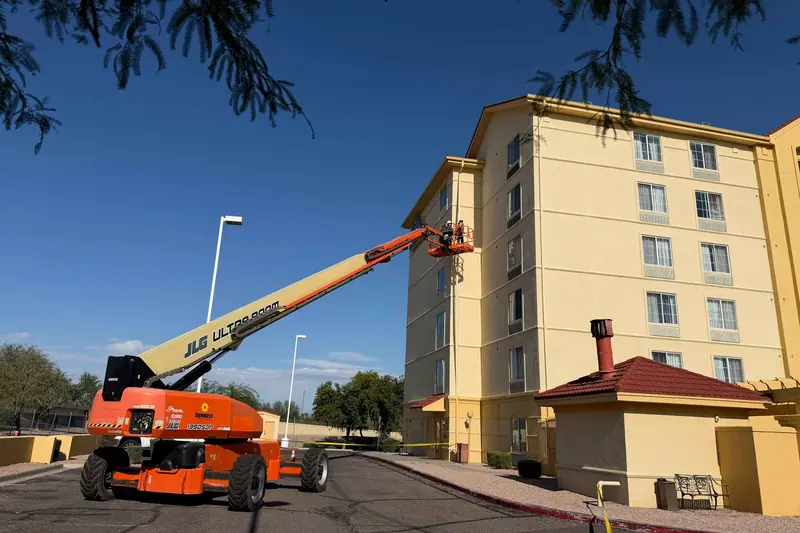 Boom lift set up against a multi story hotel exterior