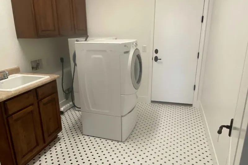 Finished laundry room with patterned tile floor and a stacked washer and dryer