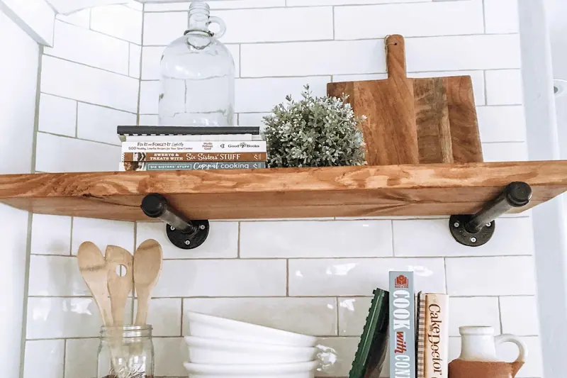 Subway tiled wall with timber open shelving on black pipe brackets
