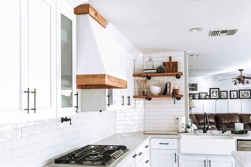 White kitchen with a floating timber shelf and a painted vent hood