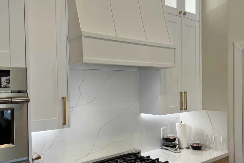 White painted vent hood over a gas range in a finished kitchen