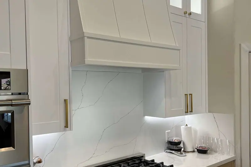 White cabinetry and hood around a wall oven and range