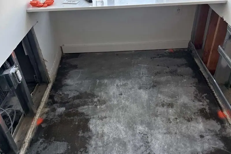 Flood cut through drywall and baseboard in a narrow room, wet slab exposed