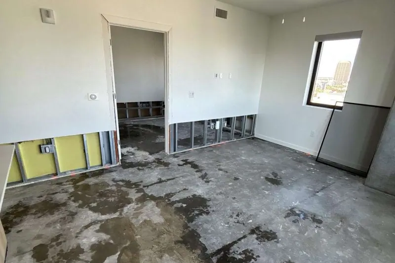 Living room stripped to the slab with a flood cut along the base of the walls