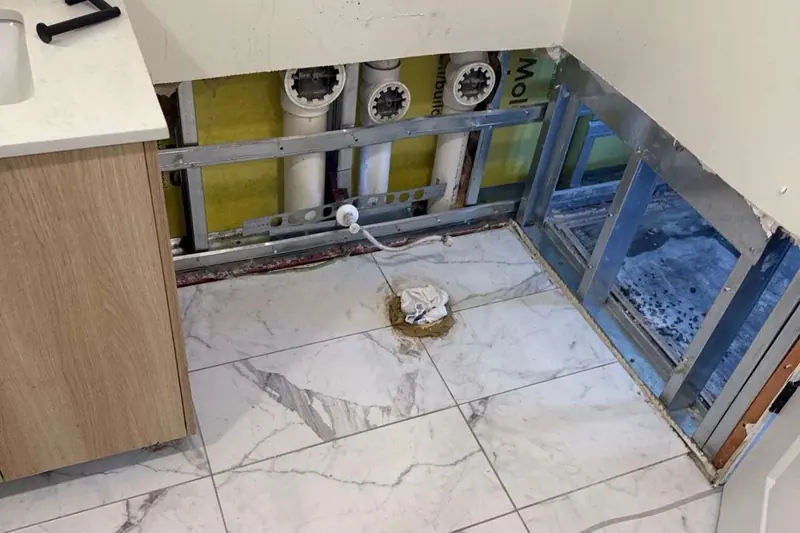 Tile floor opened in a laundry area with the wall cavities cut back to dry