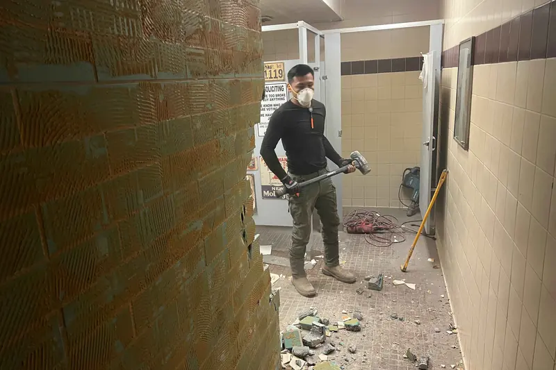 A Restored technician in a mask stripping out a contaminated tiled area