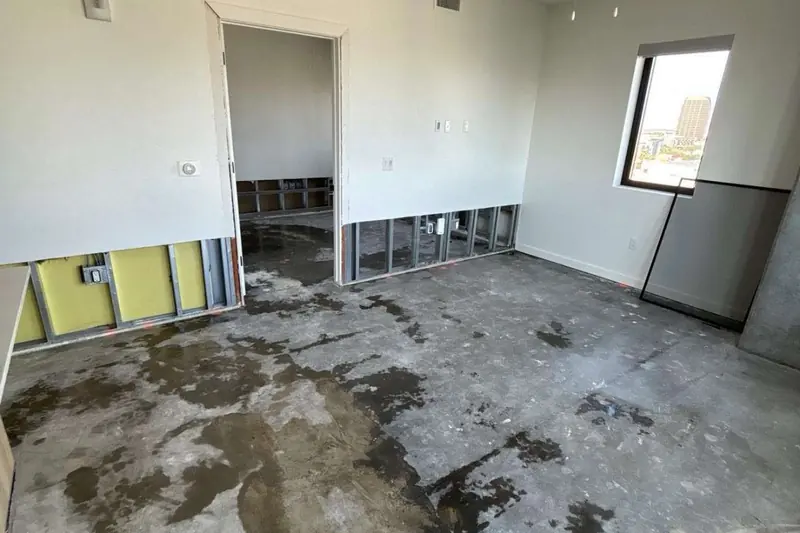 Flood-cut drywall opened to the studs above a water-damaged slab