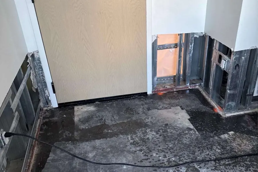 Baseboard and drywall cut away to expose wet studs and slab during a water damage job